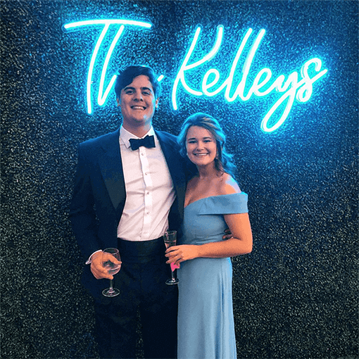 Guests standing in front of turquoise The Kelleys' last name neon sign